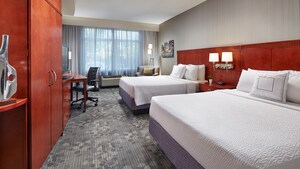 Two queen beds, an armoire, TV dresser, desk with an office chair and, beyond, an easy chair