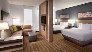 The studio features an entertainment center room divider that separates 2 double beds from the couch