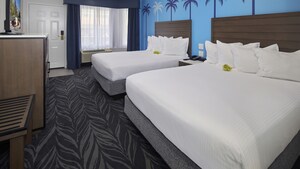 A bedroom with 2 beds, a TV, drawers and curtains