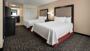 A suite with 2 queen size beds, dresser with lamp, television and kitchenette.