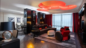 The Mickey Mouse Suite living area at the Disneyland Hotel with a dining set, desk, sofa, armchairs, Mickey Mouse lamps, framed pictures and a ceiling light fixture shaped like Mickey Mouse's head