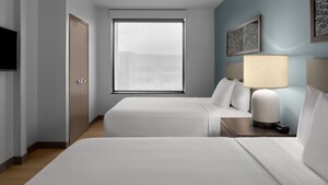 A modern bedroom with 2 queen beds, a closet and a flat screen TV