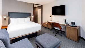 A guest room that includes 1 King bed, a desk, a television mounted on the wall and sofa bed.