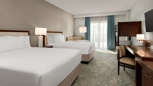 A hotel room with a desk, TV, balcony, nightstand, 2 queen beds and 2 bunk beds