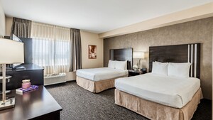 Un dormitorio con 2 camas Queen Size y una ventana con cortinas