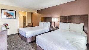 Classic Room with 2 queen size beds, side table with lamp, dresser and a closet.