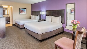 Premier room with 2 queen size beds, side table with lamp, small dining table and chair, wall mirror, dresser and artwork.