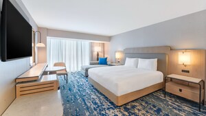 A hotel bedroom with a king bed, sofa, desk, TV, table and 2 nightstands