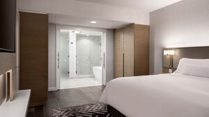 A hotel bedroom with a TV, 2 wardrobes and an adjoining bathroom. 