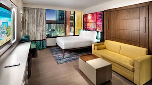 A hotel villa studio with a bed, TV, couch and 'The Princess and the Frog' themed artwork