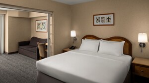 The Family Suite at Anaheim Portofino Inn and Suites featuring a king bed, 2 wall sconces, 2 side tables and a sofa
