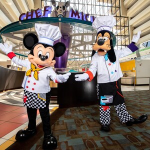 Mickey Mouse e Pateta vestidos como chefs com os braços estendidos