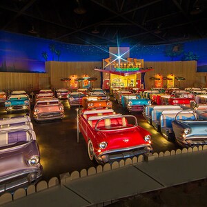 Vista frontal de fileiras de mesas estofadas de jantar em forma de carros dos anos 1950 com uma lanchonete ao fundo