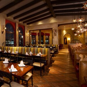 Salão de jantar do La Hacienda de San Angel com grandes janelas e teto com colunas, iluminado à noite