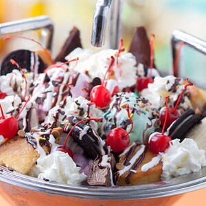 Uma tigela no formato de uma pia de cozinha repleta de sorvete, cookies, doces, bolo, chantili e frutas