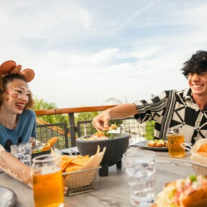 Dois Visitantes saboreando comida e bebida sentados em um deck ao ar livre no Paddlefish	