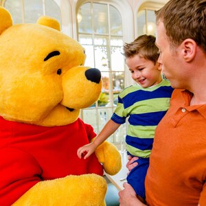 A man holding his child in his arms while talking to Winnie the Pooh in The Crystal Palace