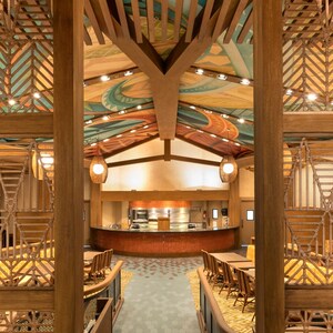 Dining hall com arquitetura inspirada na Polinésia, incluindo um mural no teto e detalhes em madeira natural