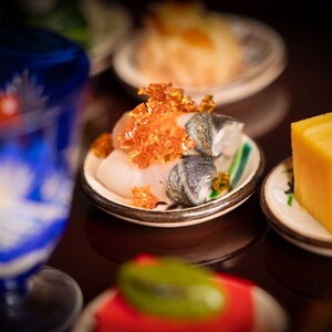 Um prato com fatias de peixe e outros ingredientes sobre uma mesa do Takumi Tei