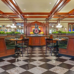 The charming interior of Tony’s Town Square Restaurant at Magic Kingdom park, with tables and chairs, ceiling fans and hanging plants