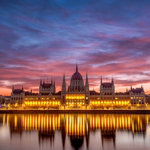 The Budapest Parliament building at sunset, with reflections of its lights on the Danube River