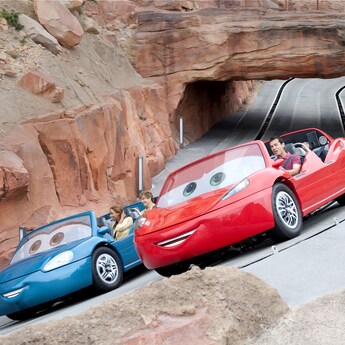 A car with Guests zoom along the tracks side-by-side at Radiator Springs Racers