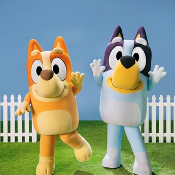 Bingo and Bluey wave hello by a picket fence