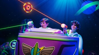 Two young Guests taking aim with their lazer blasters while riding Buzz Lightyear's Space Ranger Spin at Magic Kingdom park