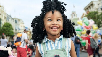 A little girl holds a Minnie Mouse plush at Magic Kingdom park