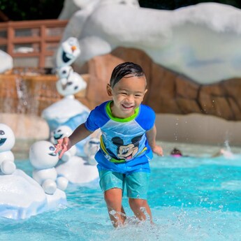 A young boy plays at Tike's Peak near statues of Olaf and Snowgies at Disney's Blizzard Beach water park