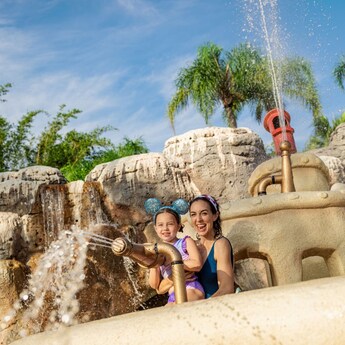 A mother and 2 daughters playing with water cannons at Disney’s Typhoon Lagoon water park