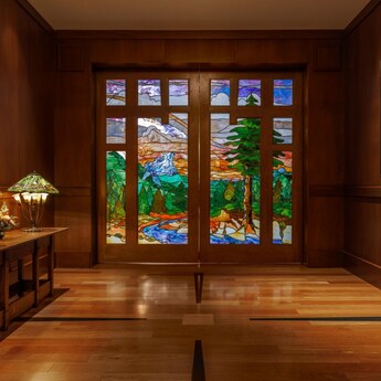 A wood paneled room at Disney's Grand Californian Hotel & Spa with stained glass doors depicting a mountain landscape