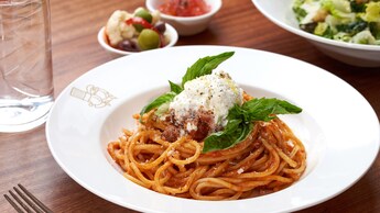 A plate of spaghetti with a side salad