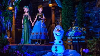 Anna, Elsa and Olaf stand in the Frozen Ever After attraction