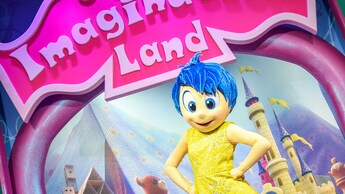 Joy se prepara para recibir a los Visitantes bajo un letrero de “Imagination Land”