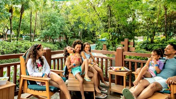 Una familia de 6 personas se relaja en una terraza junto a Cross Country Creek en Disney's Blizzard Beach Water Park