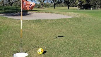 Uma bola de futebol perto de um obstáculo de areia em um campo de futegolfe