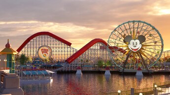 Un puente sobre un canal lleva a un arco que marca la entrada a Paradise Pier, un área con un carrusel, una enorme montaña rusa de madera y una rueda de la fortuna con la cara de Mickey Mouse en el centro.