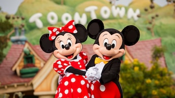 Mickey and Minnie Mouse posing in front of a sign reading Toontown