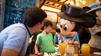 At Storytellers Cafe, Mickey Mouse is dressed as an explorer and greets a father and son.