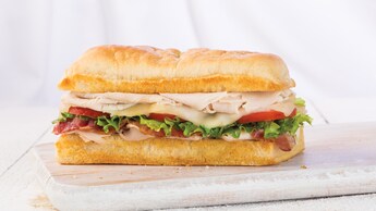 Un club sándwich con pavo, tocino, queso suizo, lechuga y tomate