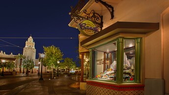 Buena Vista Street glowing at night as sweets are featured in the window display at Trolley Treats