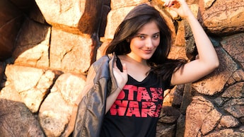 A woman holds a jacket while wearing a shirt with words that read Star Wars