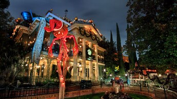 Un espantapájaros de Jack Skellington frente a Haunted Mansion decorada con motivos de fiestas