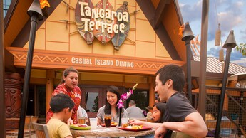 A Tangaroa Terrace server places plates in front of a family dining outside