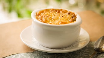 Sopa de cebola francesa em uma tigela sobre um pires com guardanapo rendado de papel