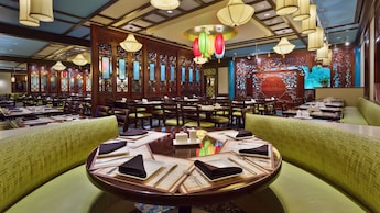 Cabine circular para 6 no salão de jantar com lanternas asiáticas e painéis de madeira decorativos