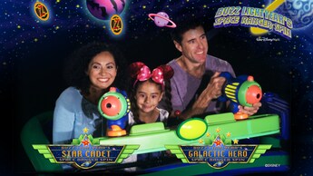Un hombre, una mujer y su hija en un vehículo de la atracción Buzz Lightyear's Space Ranger Spin