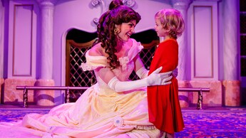 Belle speaks with a young child in front of a fireplace