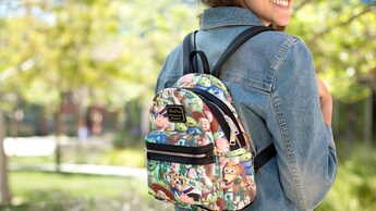 A woman wearing a small backpack with a Toy story themed graphic print